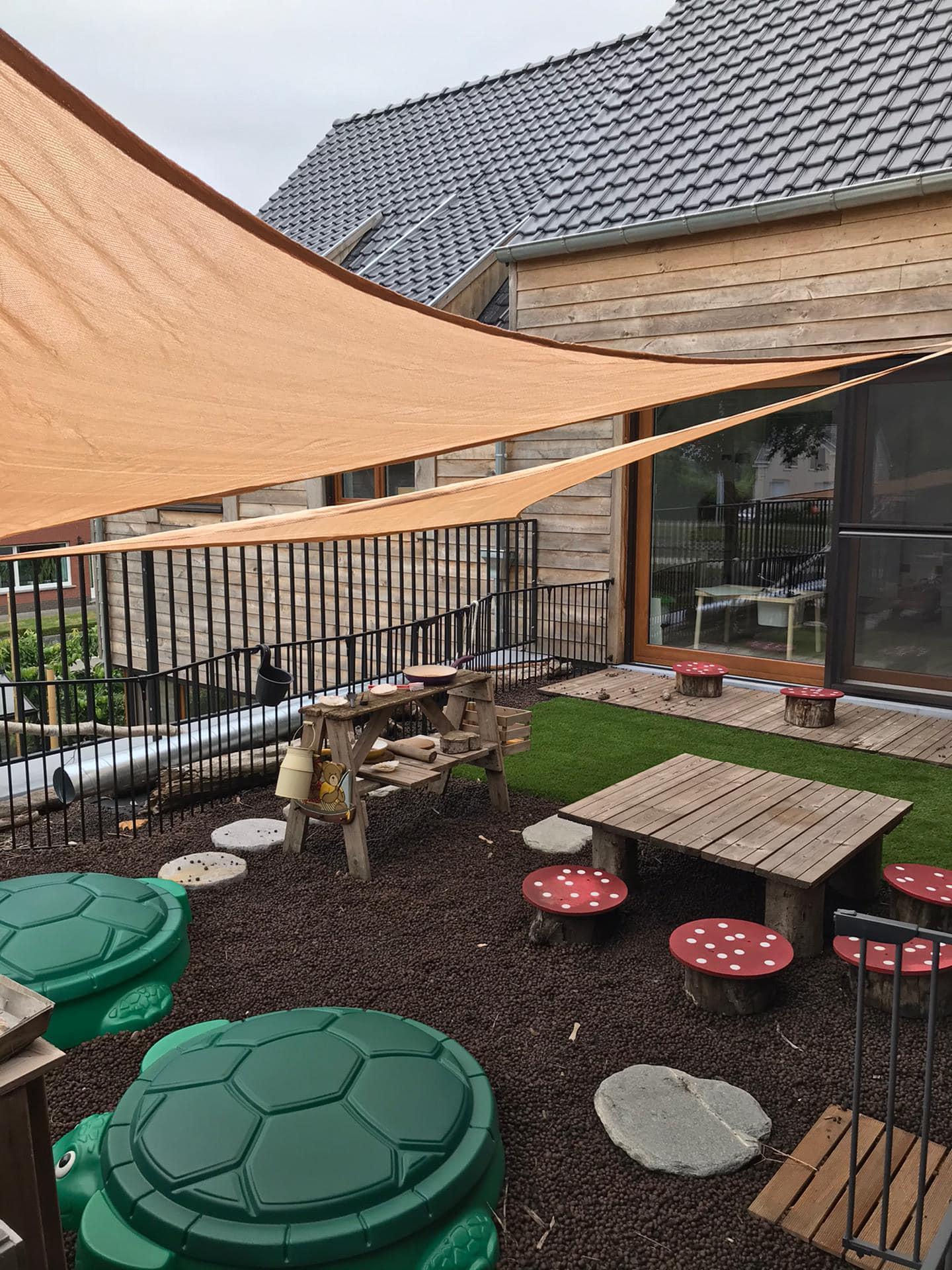 Tuin met zonnezeilen en houten speelhuisje